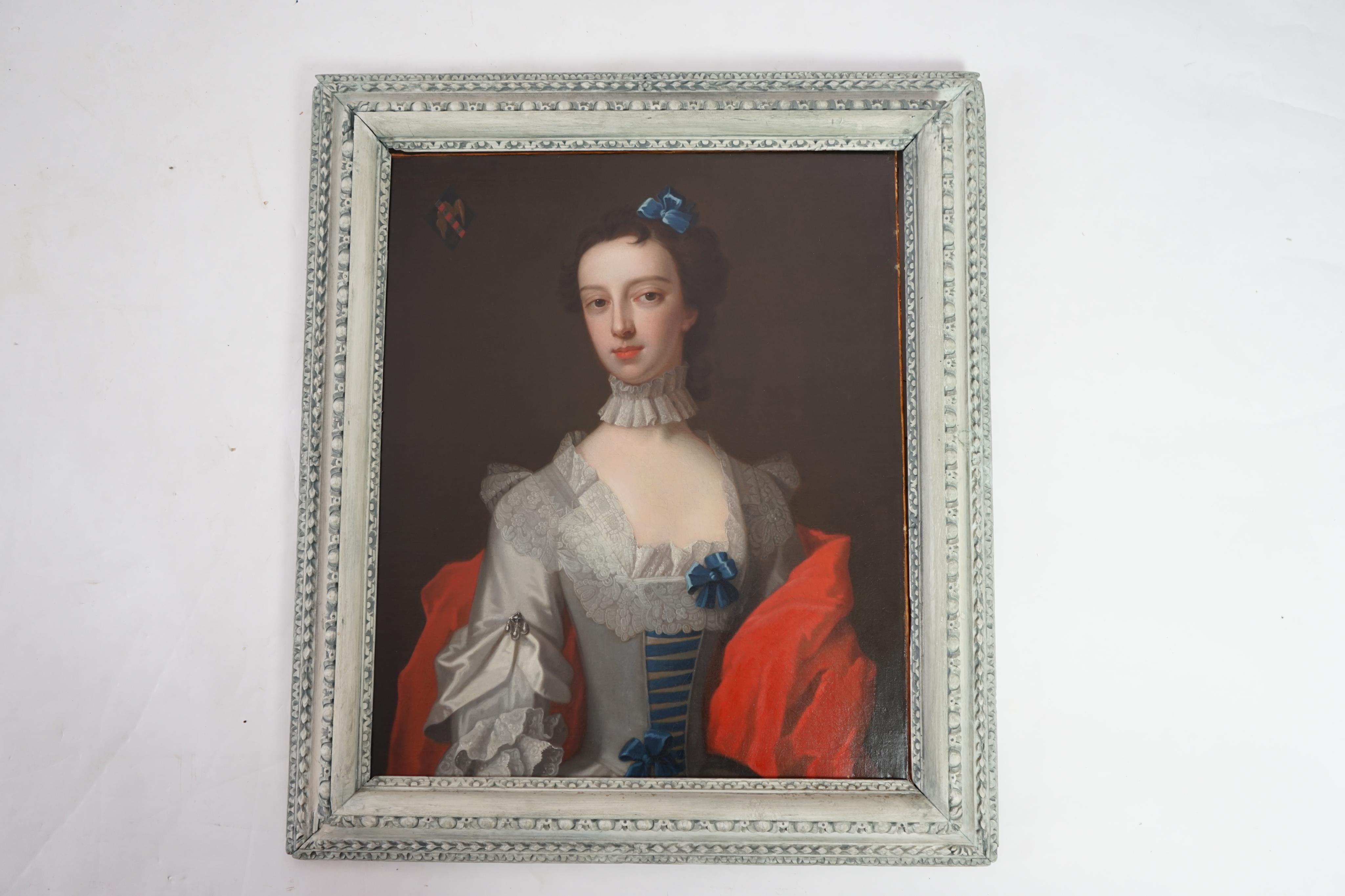 Attributed to Enock Seeman (c.1694-1745), Half length portrait of a lady with blue ribbon in her hair, elaborate lace collar and crimson robe, an armorial to the top left, oil on canvas, 74 x 62cm